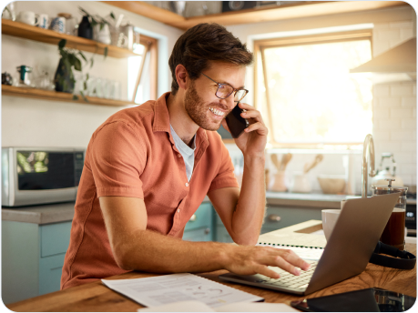 Man talking on phone while working on laptop